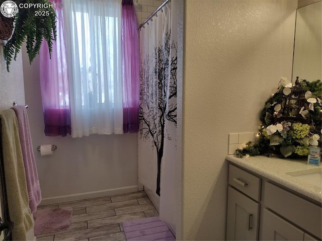 full bath featuring baseboards, vanity, a wealth of natural light, and wood tiled floor