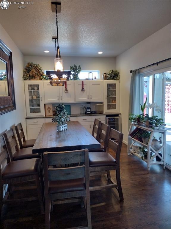 dining room featuring a textured ceiling, wine cooler, and dark wood-style flooring