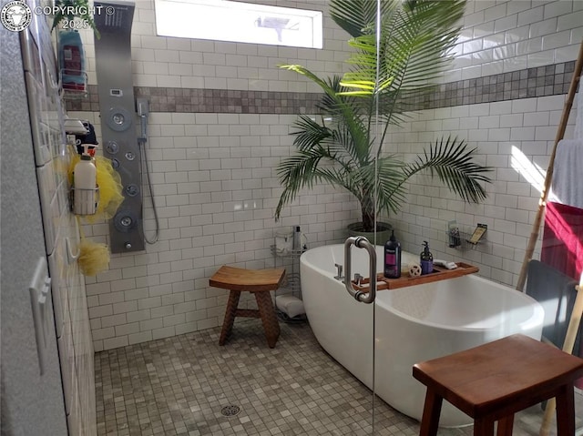 full bath with a soaking tub, a tile shower, tile walls, and tile patterned floors