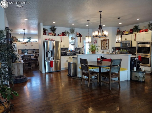 dining room with recessed lighting, dark wood finished floors, a textured ceiling, and an inviting chandelier