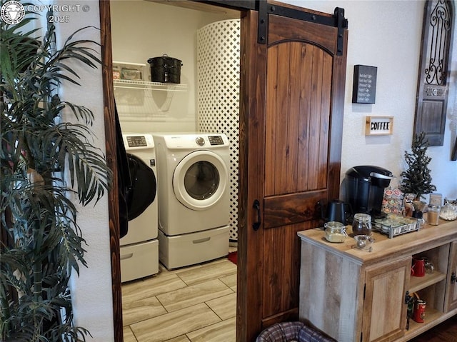 laundry area featuring laundry area, a barn door, washer and clothes dryer, and wood tiled floor