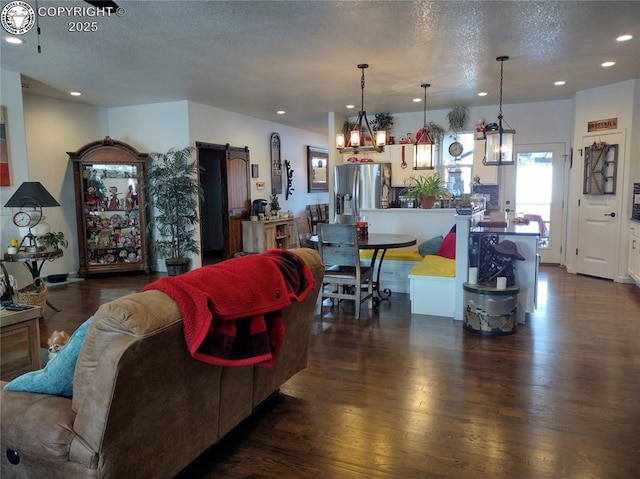 living room with a textured ceiling, a barn door, dark wood-style flooring, and recessed lighting