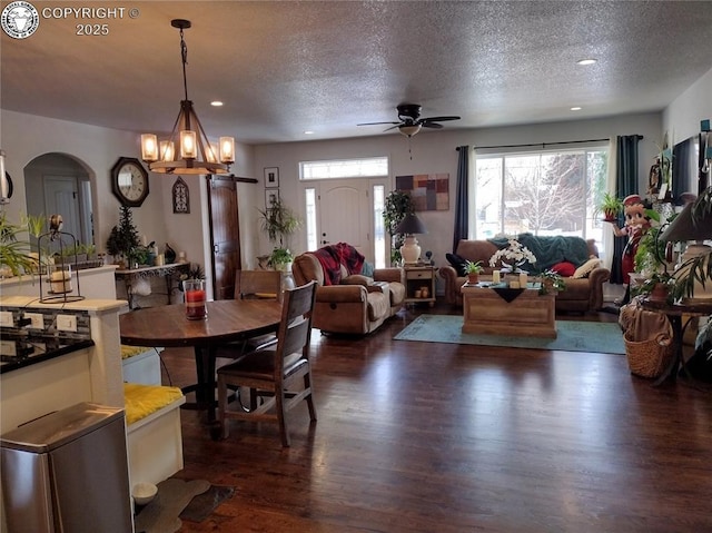 dining space with dark wood-type flooring, a wealth of natural light, arched walkways, and a textured ceiling