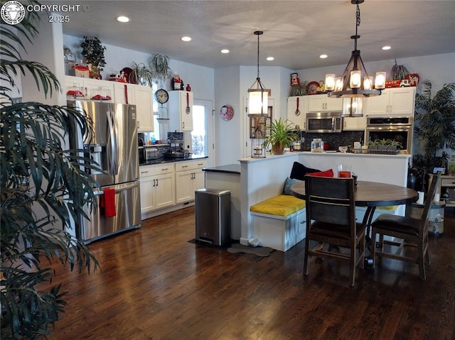 kitchen featuring decorative backsplash, dark wood-style flooring, decorative light fixtures, stainless steel appliances, and white cabinetry