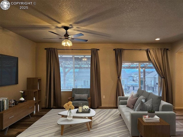 living room featuring ceiling fan, dark hardwood / wood-style flooring, a healthy amount of sunlight, and a textured ceiling