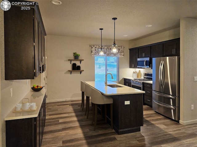 kitchen with sink, a breakfast bar area, decorative light fixtures, a center island with sink, and stainless steel appliances