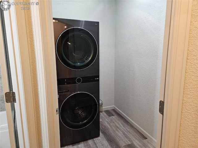 laundry area with stacked washer and dryer and wood-type flooring