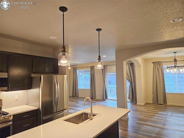 kitchen featuring a kitchen island, appliances with stainless steel finishes, decorative light fixtures, sink, and dark brown cabinets