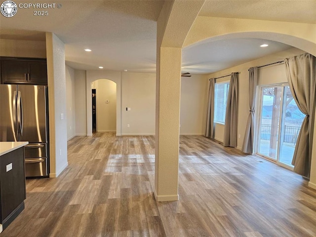 interior space with dark brown cabinetry, light hardwood / wood-style flooring, stainless steel refrigerator, and a textured ceiling