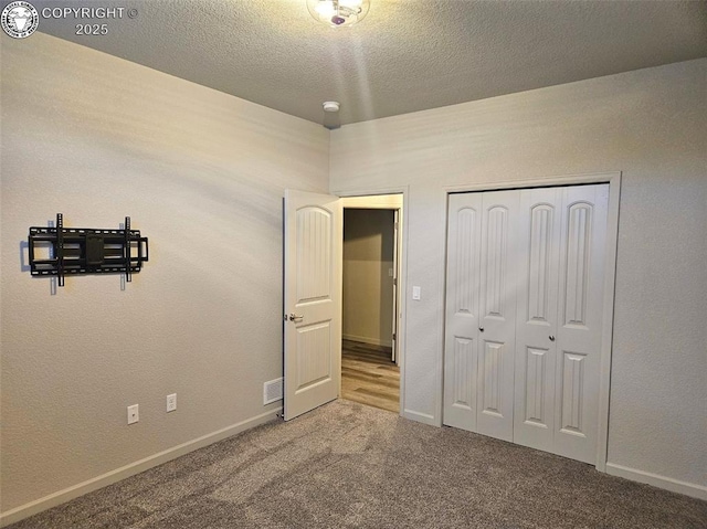 unfurnished bedroom with carpet floors, a textured ceiling, and a closet