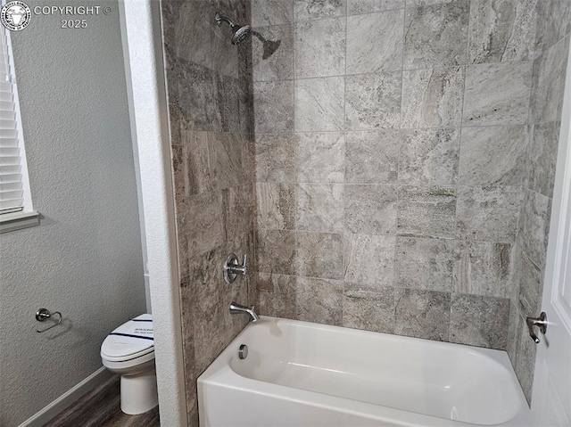 bathroom featuring wood-type flooring, toilet, and tiled shower / bath combo