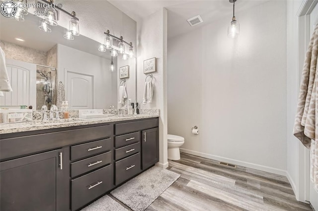 bathroom featuring walk in shower, vanity, toilet, and hardwood / wood-style floors