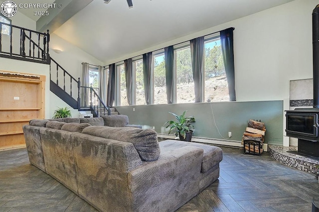 living area featuring stairs, a baseboard radiator, lofted ceiling, and a wood stove