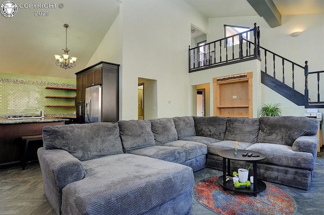 living area with stairway, a notable chandelier, beamed ceiling, and a towering ceiling