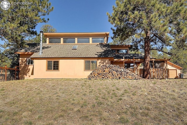 rear view of property with a yard, stucco siding, and a shingled roof