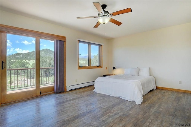 bedroom with a baseboard radiator, hardwood / wood-style flooring, access to exterior, ceiling fan, and a mountain view