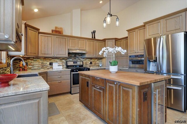 kitchen featuring appliances with stainless steel finishes, a center island, backsplash, and wood counters