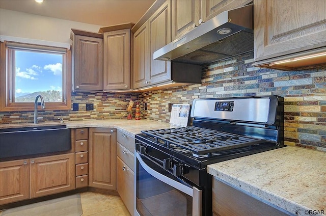 kitchen featuring light tile patterned flooring, sink, backsplash, gas range, and light stone countertops