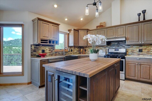 kitchen featuring butcher block countertops, appliances with stainless steel finishes, wine cooler, a kitchen island, and vaulted ceiling