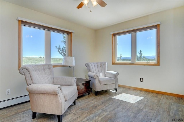 living area featuring a baseboard heating unit, hardwood / wood-style floors, and ceiling fan