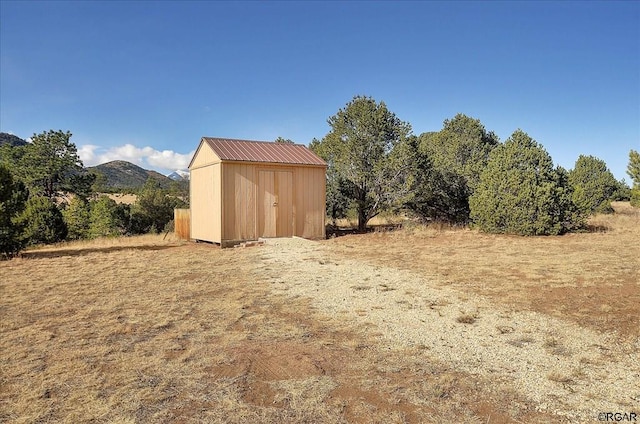 view of yard with a rural view, a mountain view, and a storage shed