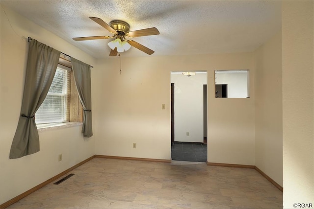 empty room with ceiling fan and a textured ceiling