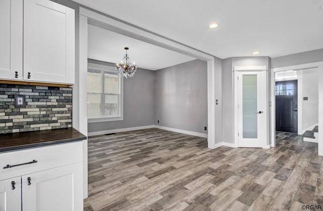 kitchen with white cabinetry, decorative light fixtures, tasteful backsplash, and light hardwood / wood-style floors