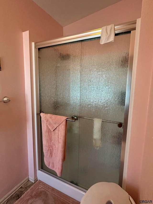 bathroom featuring a shower with shower door and toilet