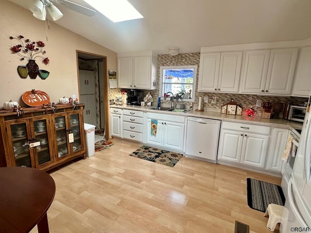 kitchen featuring lofted ceiling with skylight, sink, dishwasher, light hardwood / wood-style floors, and white cabinets