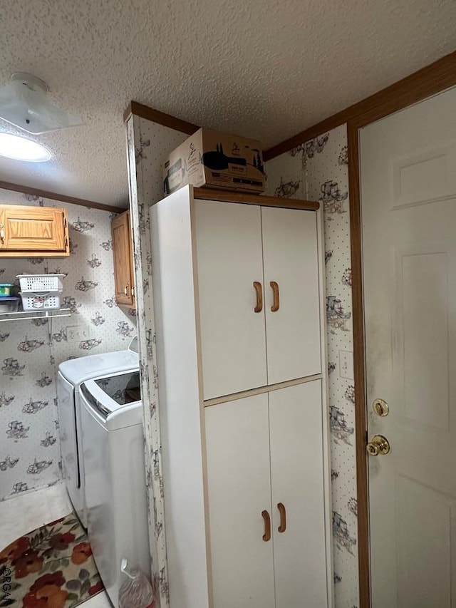 laundry area with independent washer and dryer, crown molding, cabinets, and a textured ceiling