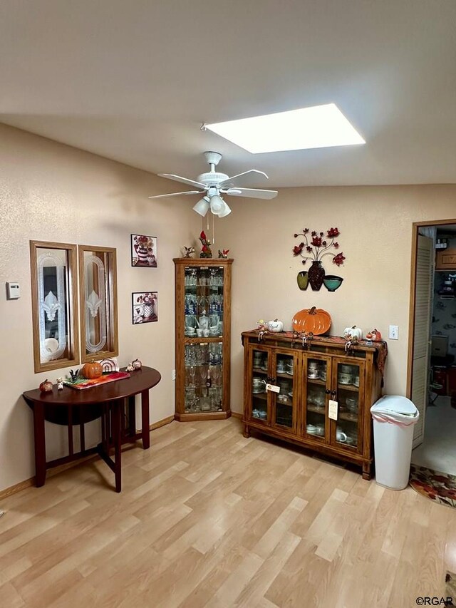 miscellaneous room with a skylight, ceiling fan, and light wood-type flooring