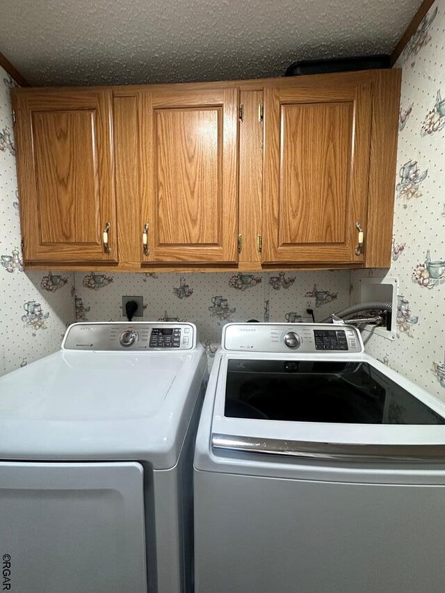 laundry room featuring cabinets, a textured ceiling, and washer and clothes dryer