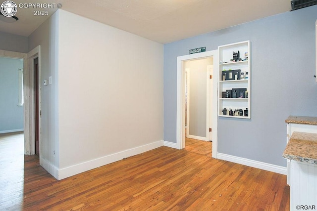 empty room featuring hardwood / wood-style floors and built in features