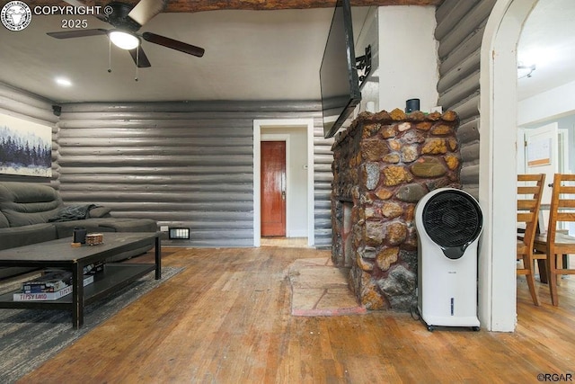 living room featuring ceiling fan, rustic walls, and hardwood / wood-style floors