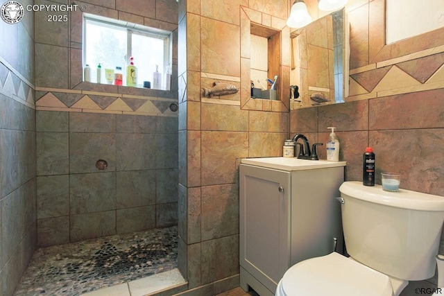 bathroom featuring tile walls, tiled shower, vanity, decorative backsplash, and toilet