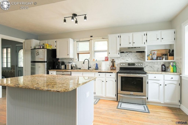 kitchen featuring sink, white cabinetry, stainless steel appliances, light stone counters, and a kitchen island