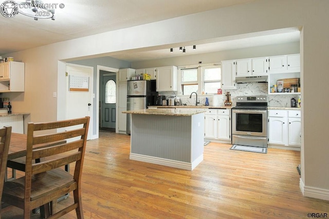 kitchen featuring a kitchen island, white cabinets, light stone counters, light hardwood / wood-style floors, and stainless steel appliances