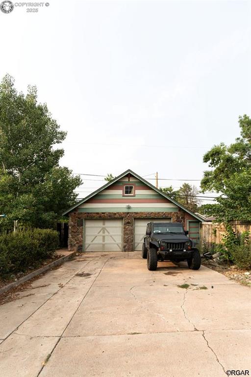 view of front of house with a garage and an outbuilding