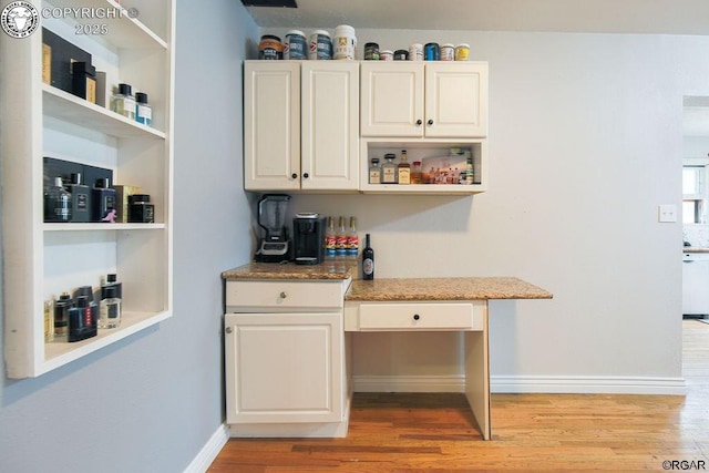 bar with white cabinetry, light stone countertops, and light hardwood / wood-style flooring