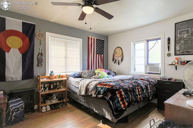 bedroom featuring cooling unit, light hardwood / wood-style flooring, and ceiling fan