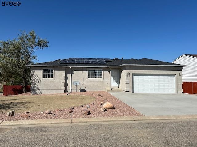 ranch-style house featuring a garage, a front lawn, and solar panels