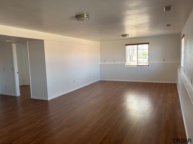 unfurnished room featuring dark wood-type flooring and a textured ceiling