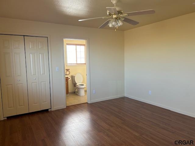 unfurnished bedroom featuring ceiling fan, dark hardwood / wood-style floors, and a closet