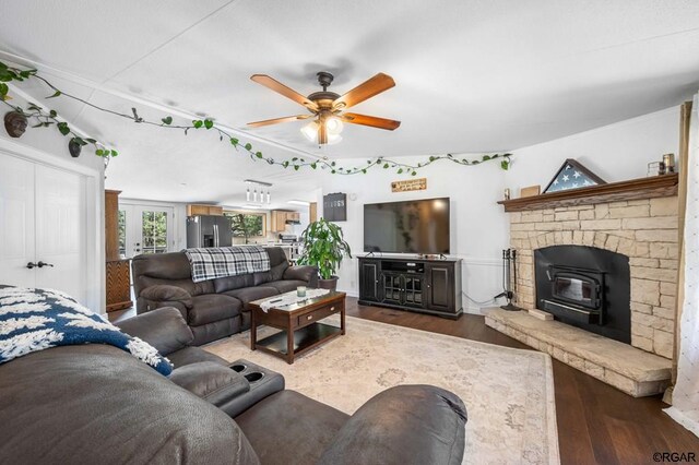 living room with dark hardwood / wood-style flooring, ceiling fan, and a wood stove