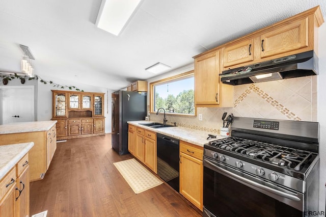 kitchen with lofted ceiling, sink, dark wood-type flooring, stainless steel appliances, and decorative backsplash