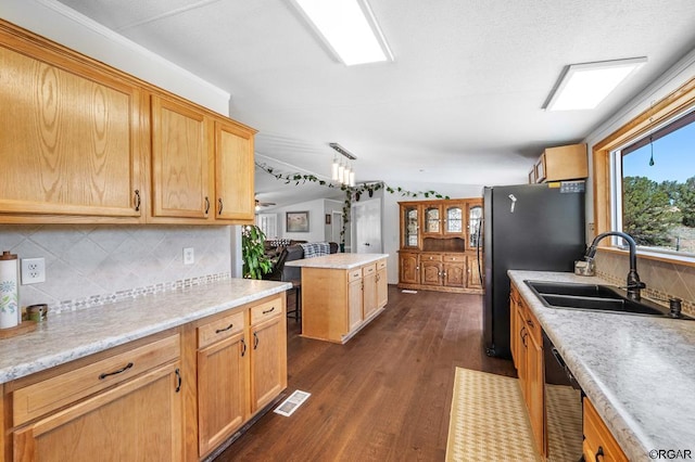 kitchen featuring a kitchen island, sink, decorative backsplash, stainless steel appliances, and dark wood-type flooring