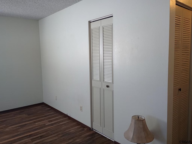 unfurnished bedroom with dark wood-type flooring and a textured ceiling