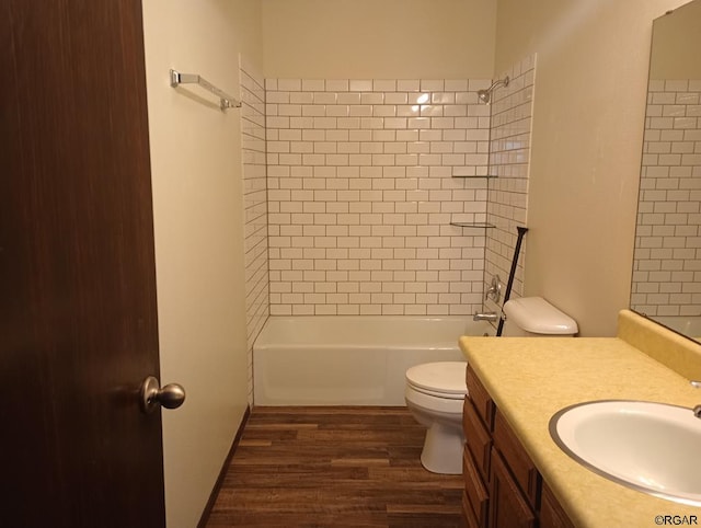 full bathroom with hardwood / wood-style flooring, vanity, tiled shower / bath, and toilet