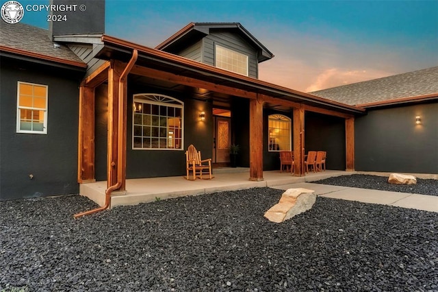 back house at dusk featuring a patio