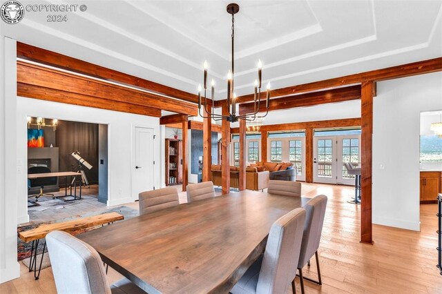 dining space with a notable chandelier, a raised ceiling, and french doors